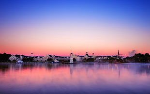 white concrete mansion beside body of water during pink sunset