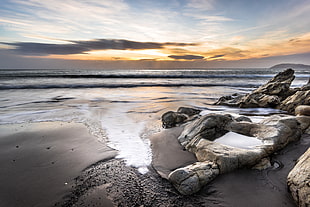 photo of a seashore with rocks during sunset, white rock, dalkey, ireland