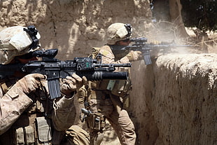 two men's holding black assault rifles during daytime