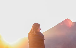 woman in black top near mountain during yellow sunset