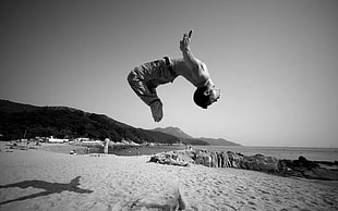 grayscale photo of man back tumbling on seashore, monochrome, jumping, men, beach