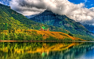 landscape photography of house in the middle of the mountain near body of water