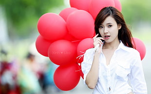 woman wearing white button-up pocket shirt holding red balloons