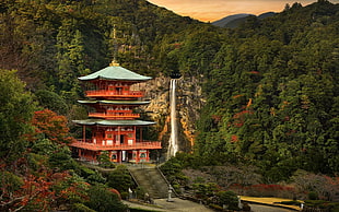 red and green temple beside forest