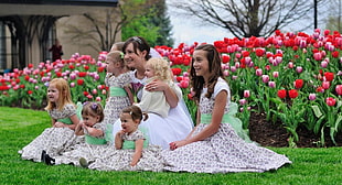 girls and mother in dress taking picture sitting on green grass