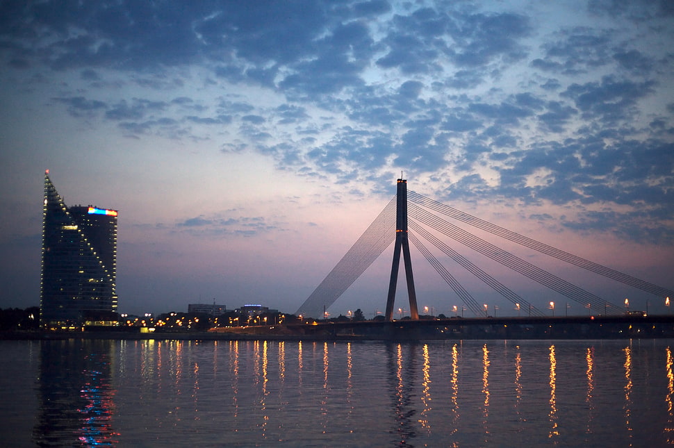 orange-lighted bridge under cloudy skies, riga HD wallpaper