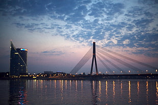 orange-lighted bridge under cloudy skies, riga