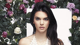 woman in white halter neck top standing in front of flower hedge