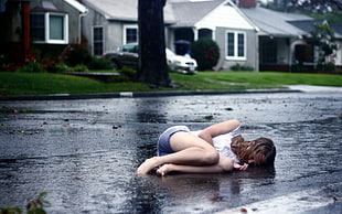 woman in white shirt and purple shorts lying on gray wet floor