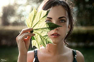 woman holding green maple leaf