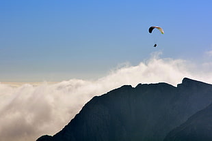 aerial photo of man with parachute near mountain peak