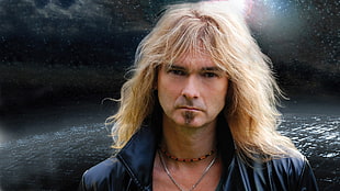 man with long blonde hair with collared jacket near the body of water