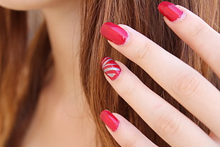 selective focus photography of women's red manicure
