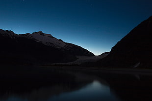 silhouette photo of lake between mountain cliffs during night time