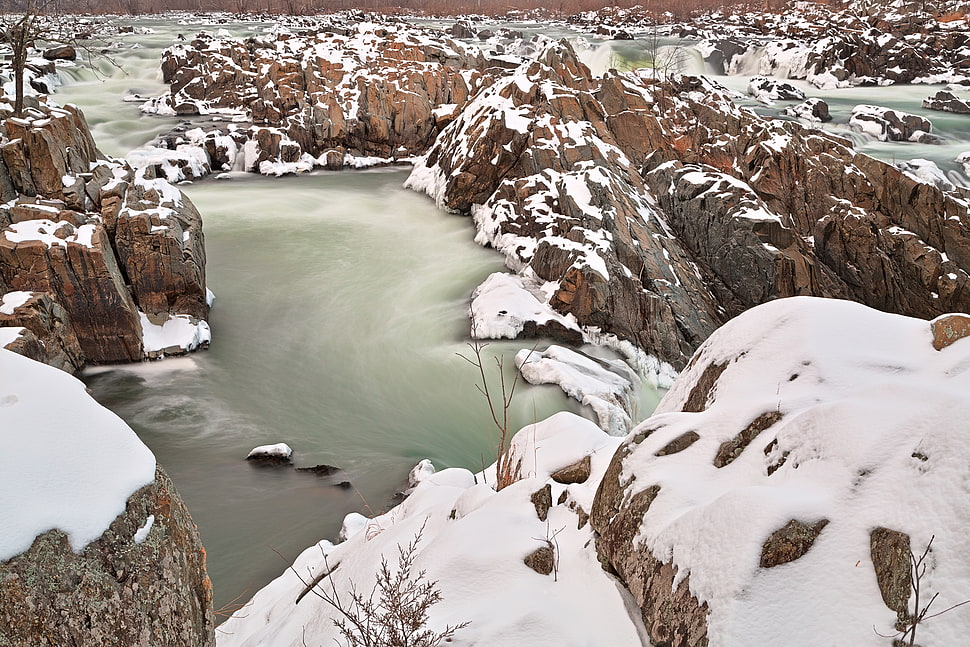 body of water surrounded by snow filled rock formation HD wallpaper