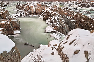 body of water surrounded by snow filled rock formation