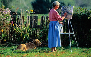 woman wearing pink and blue dress doing painting