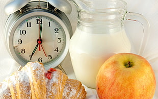 round gray analog desk clock at 7:00 near apple fruit