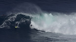 photo of person riding surfboard with huge wave during daytime
