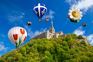 selective focus photography of flying hot air balloons on top of brown castle, mont saint-michel
