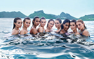 group of women in water near green mountains during daytime