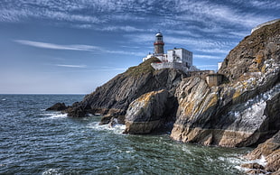 white lighthouse on gray rock beside body of water HD wallpaper
