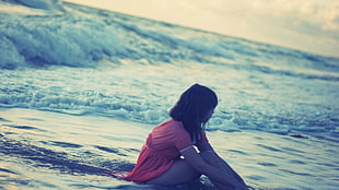 photo of woman sitting on beach shore