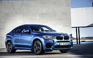 blue BMW M3 beside grey concrete wall