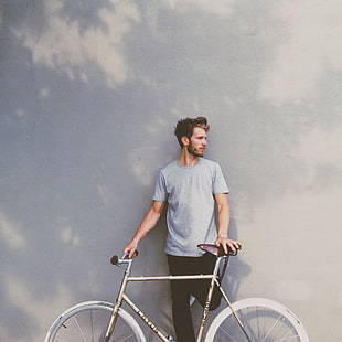 man standing near wall holding bike