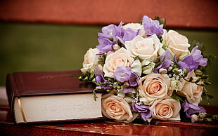 white and purple flowers beside brown covered book