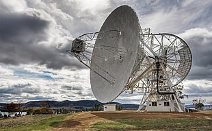 landscape photography of parabolic satellite surrounded by grass under nimbus clouds background