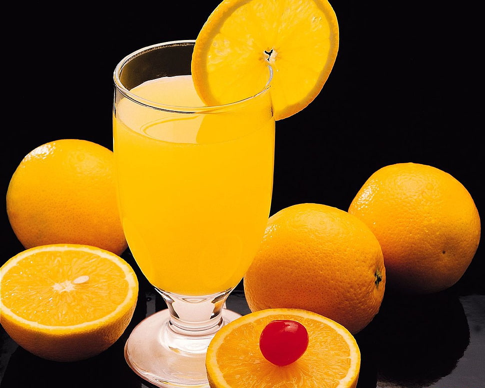 clear footed container with lemon liquid inside surrounding by lemon fruits HD wallpaper
