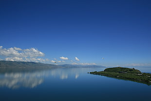 island in the middle of body of water under blue sky HD wallpaper