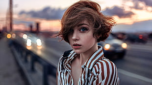 woman in brown and white striped collared shirt near roadway