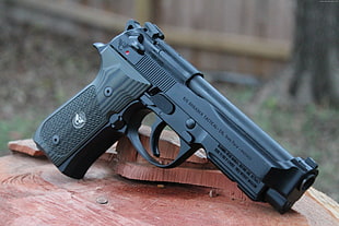 black semi-automatic pistol on brown wooden surface