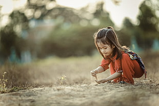 close-up photography of girl playing on sand