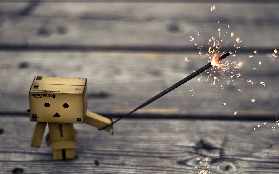 lonely box man holding sparkler on gray wooden surface HD wallpaper