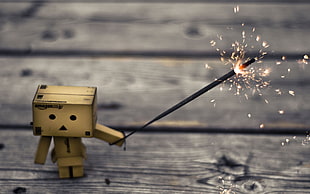 lonely box man holding sparkler on gray wooden surface