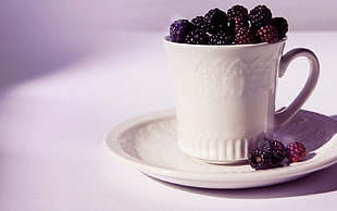 photography of raspberries in white ceramic teacup