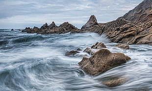 gray rocks along bodies of water painting