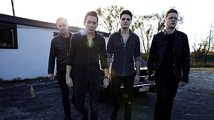 four man in long-sleeved shirts standing near a house