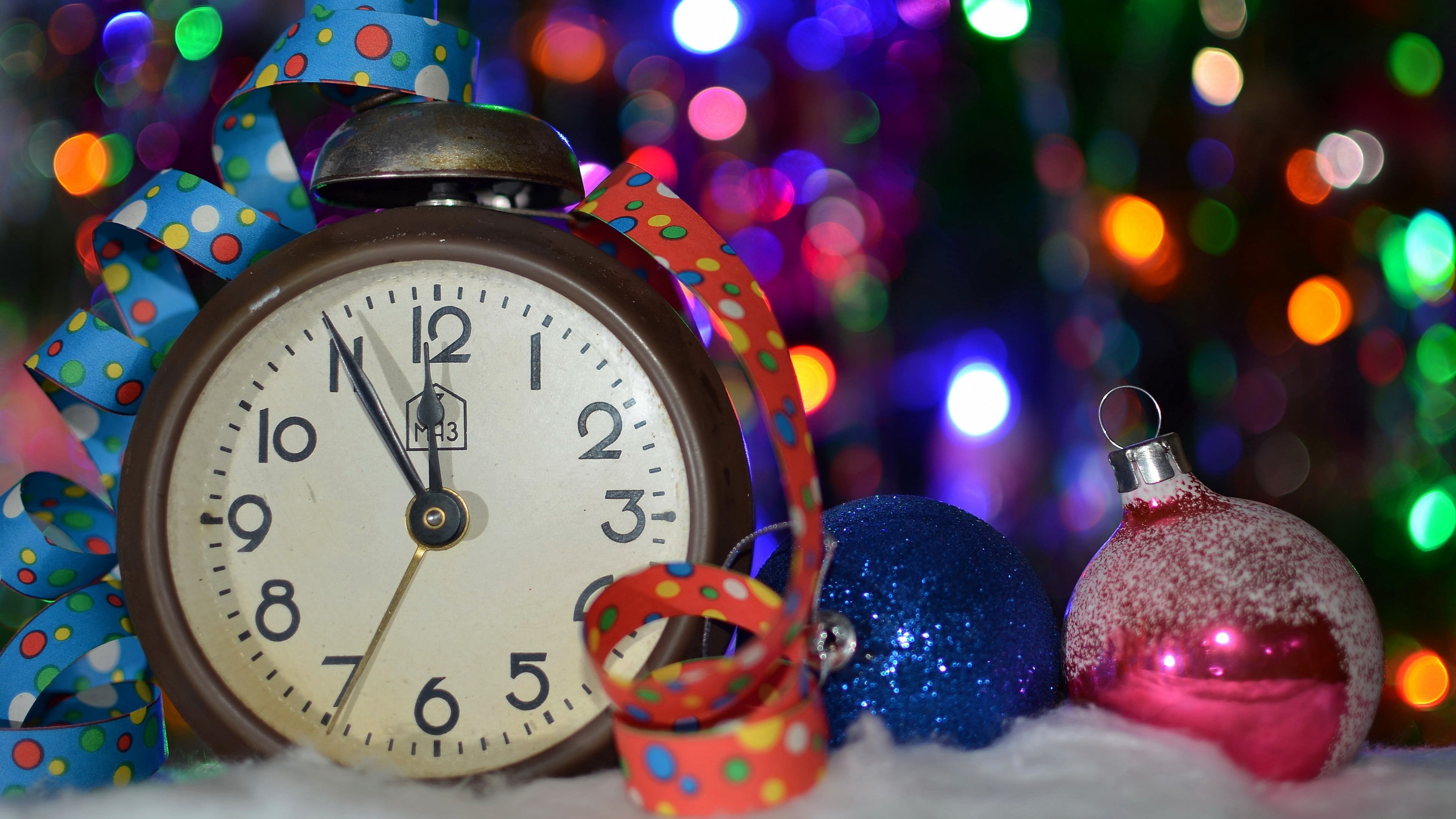 round white analog desk clock beside blue and pink baubles