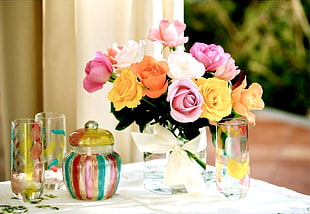white and multicolored Rose Flowers near clear glass bottles