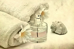 clear glass perfume spray bottle with two white towels