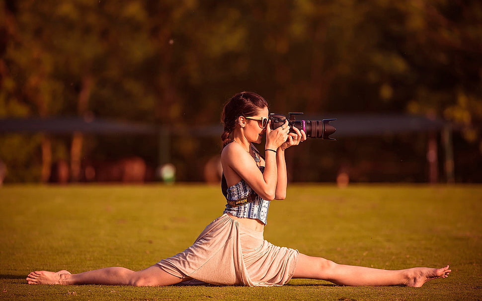woman doing a leg split while taking photo using DSLR camera HD wallpaper