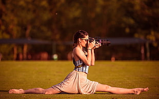 woman doing a leg split while taking photo using DSLR camera