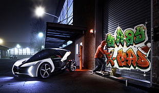 white and black luxury car near gray shutter door with green and orange graffiti