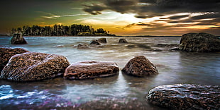 landscape photography of rocks on body of water under cloudy sky