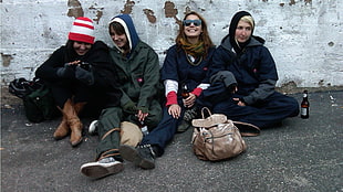 four people wearing black jacket sitting on street