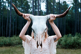 woman wearing white floral clothes holding animal skull